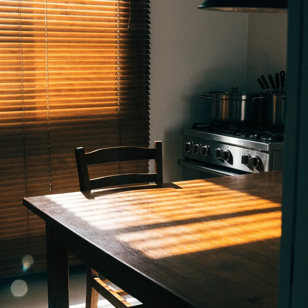 Mesa de cocina de madera en una casa española con una silla retirada y luz lateral de la ventana